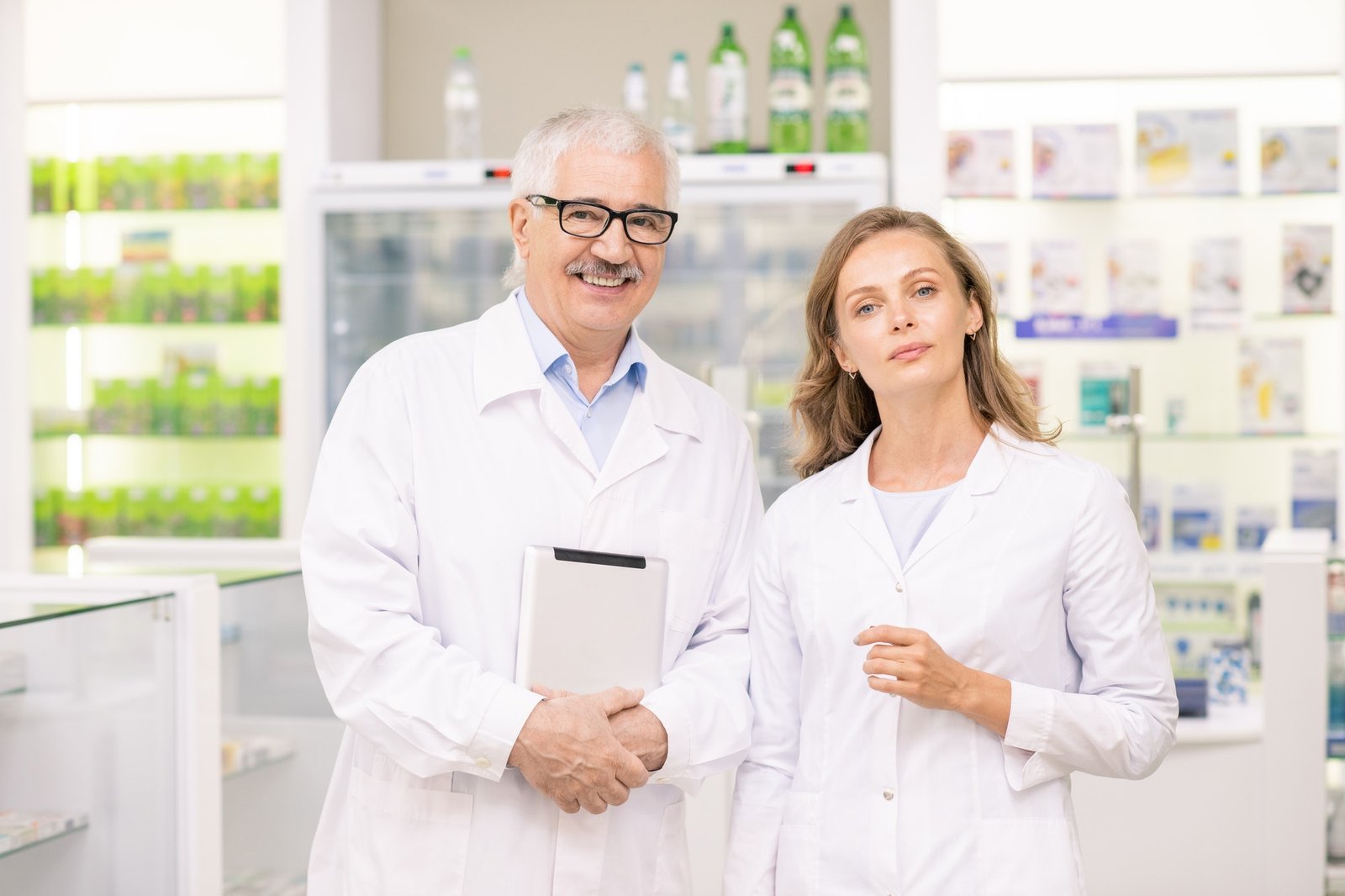pretty-blond-female-pharmacist-and-her-senior-colleague-in-whitecoats.jpg